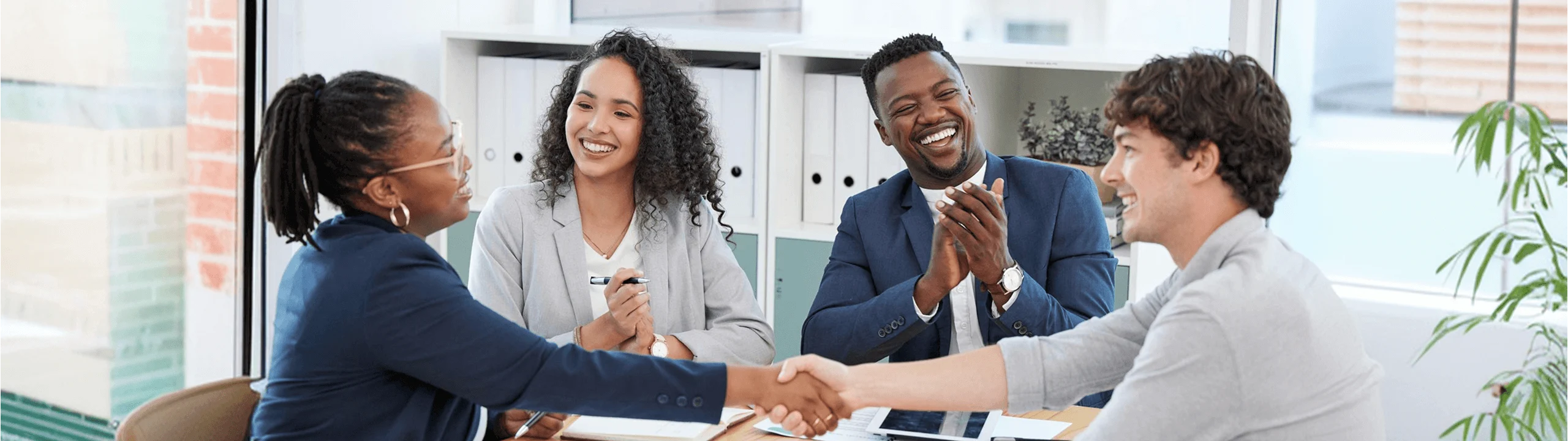 Business partners shaking hands across a meeting table